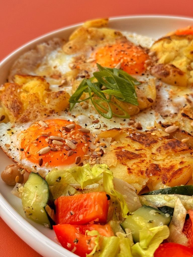 Fried eggs on potatoes with salad
