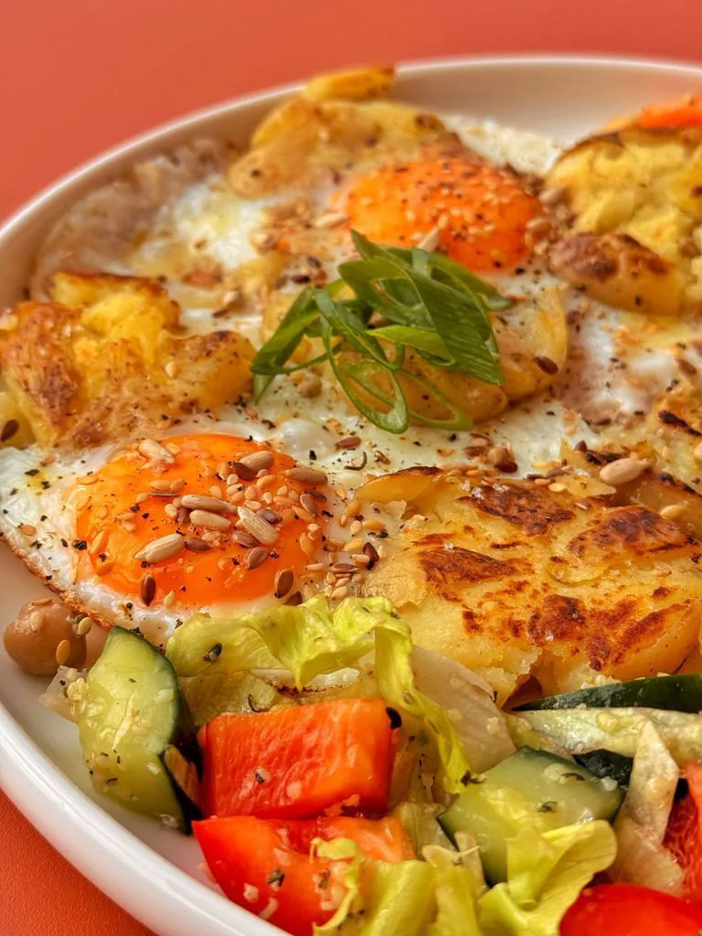Fried eggs on potatoes with salad