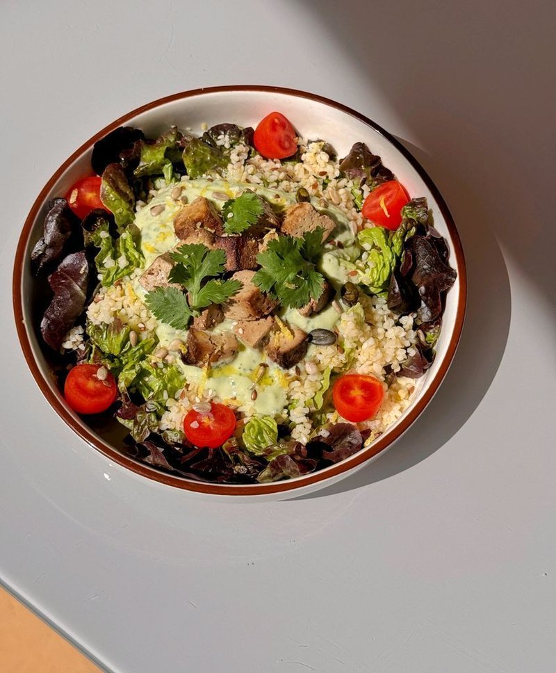 Bowl of bulgur, tofu, avocado sauce with seeds